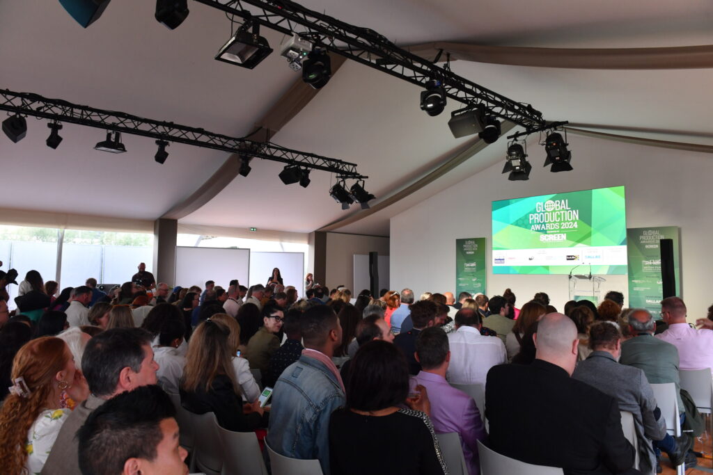 Audience seated inside a tent watching the Global Production Awards 2024 on a large screen